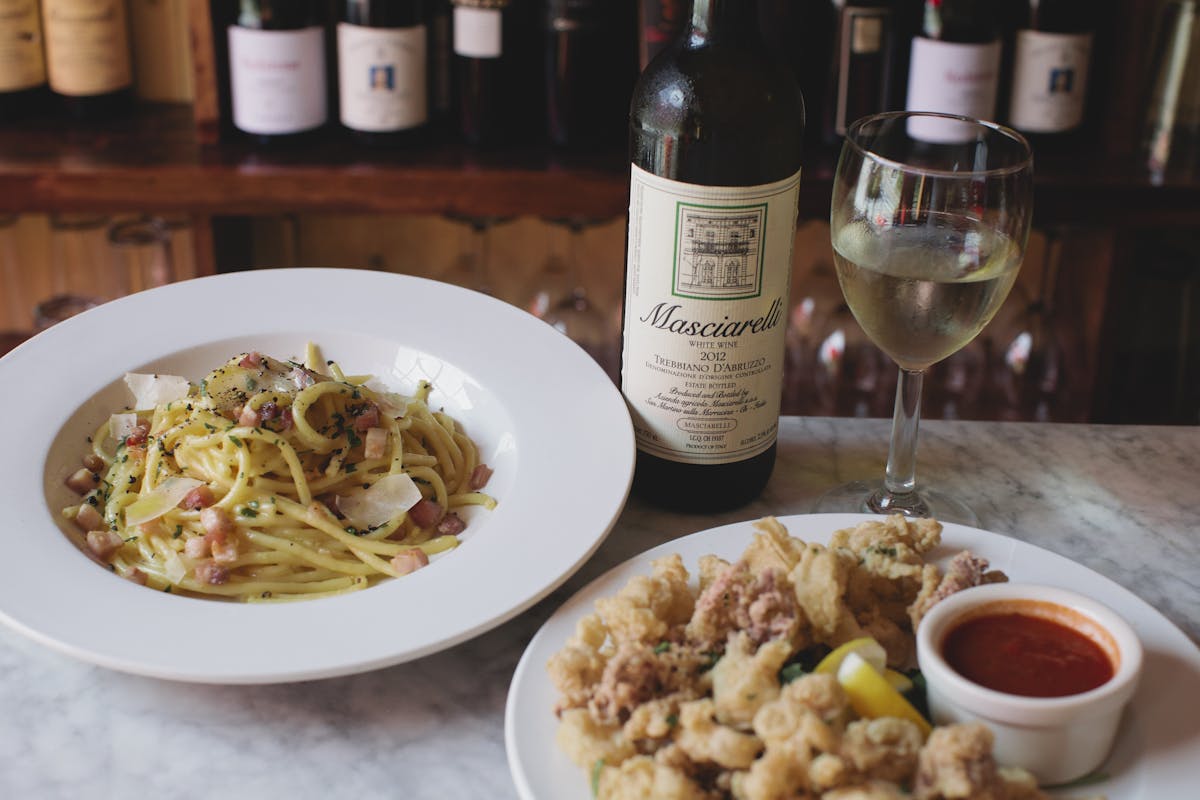 a close up of a plate of food and a bottle of wine